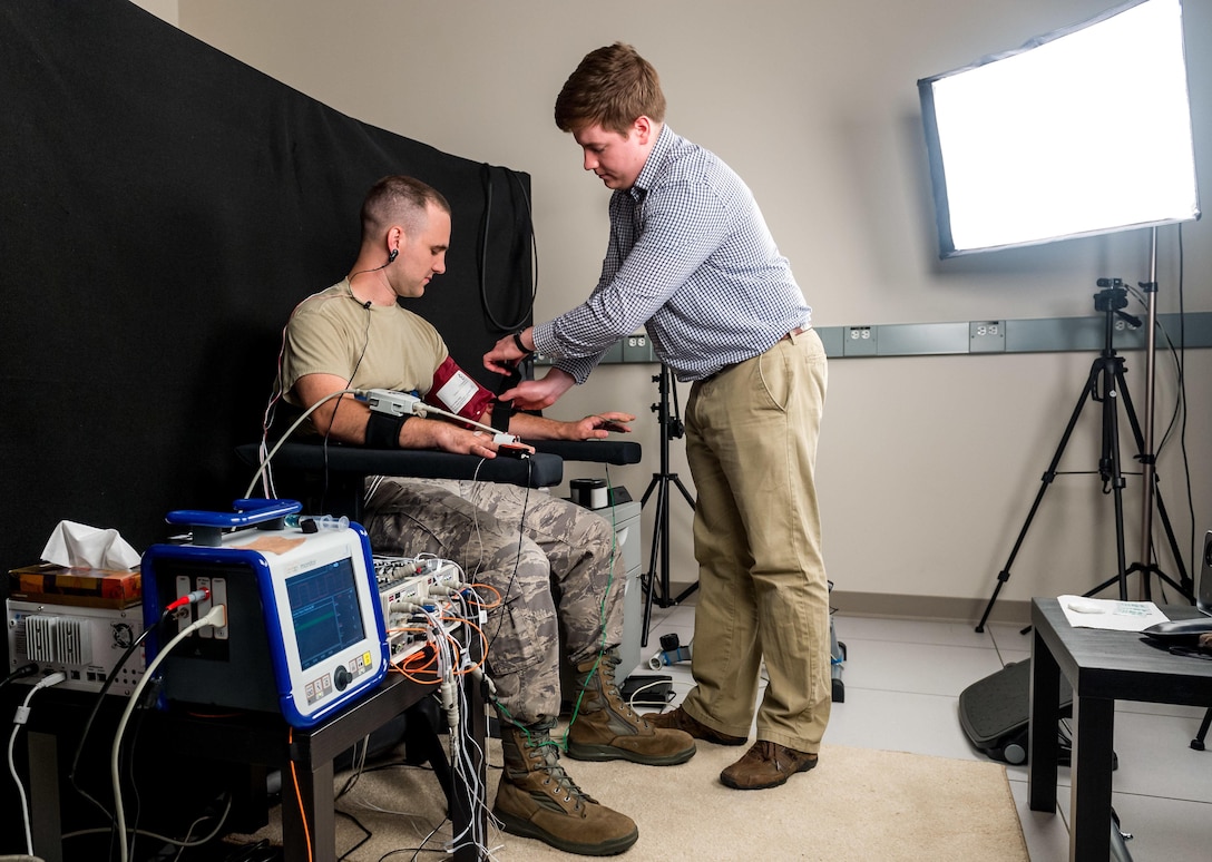 Biomedical engineer Ethan Blackford attaches sensors to test subject Air Force Staff Sgt. Josh Whicker to collect biometric data.