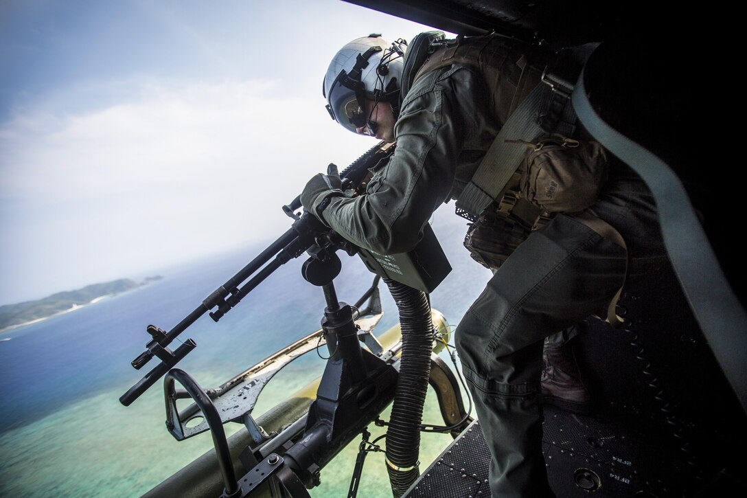 A Marine aims a weapon at his training target from a helicopter.