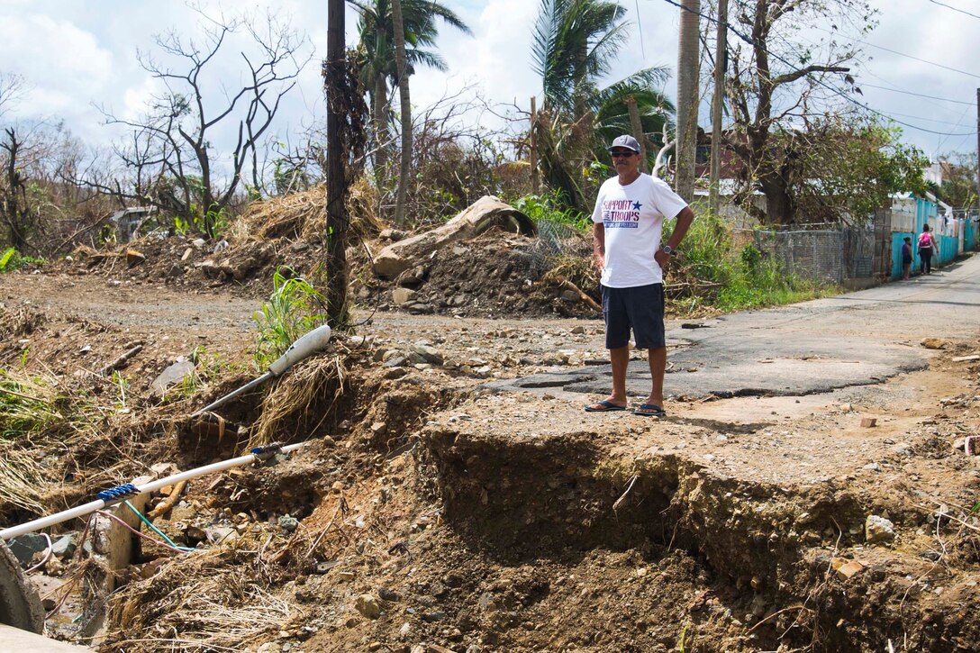 A civilian stands near a missing section of road.