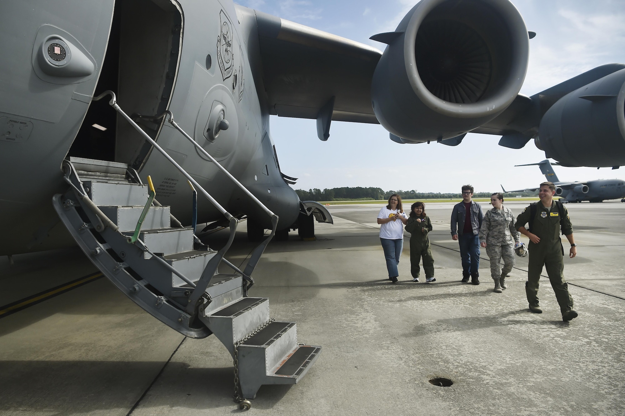 Sandrea Hershey, center left, 14 years old, her mother Lori Hershey, left, and friend Justin Pippin, center, follow Capt. Keane Carpenter, right, 437th Airlift Wing C-17 Globemaster III pilot, to a C-17 as part of an Airman for a Day event here, Oct. 2, 2017. The event was hosted by the 628th Air Base Wing and 437th AW.  Hershey was diagnosed with cancer in 2015 and spent approximately 170 days in a hospital. Despite her diagnosis Hershey kept up with her school work and finished her last treatment last month. Sandrea, her mother and her friend, were also able to meet 628th Security Forces Squadron Phoenix Raven members, observed a military working dog demonstration and test their piloting skills in a C-17 flight simulator. (U.S. Air Force photo by Staff Sgt. Christopher Hubenthal)