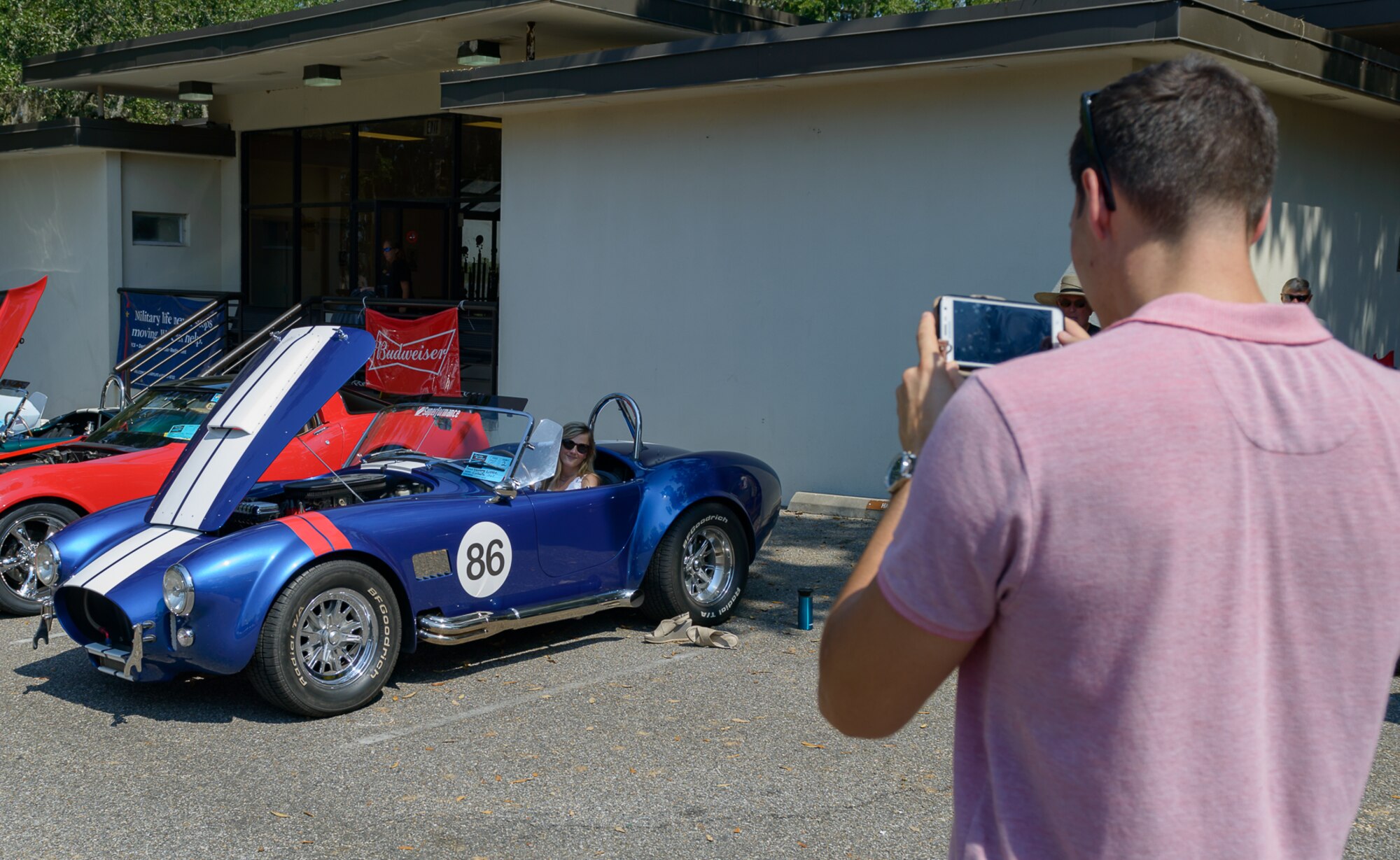 Maj. David Gentile, 403rd Wing 53rd Weather Reconnaissance Squadron WC-130J pilot, takes a picture of his wife, Jennifer Gentile, as she sits in a 1965 Superformance MK III Cobra at The Marina Park during the 14th Annual Cruisin’ Keesler Car Show Sept. 30, 2017, on Keesler Air Force Base, Mississippi. The annual car show is held to kick off Cruisin’ the Coast, a festival to celebrate classic cars, trucks and hot rods, where vehicles cruise down the 30-mile beachside highway in Mississippi. There were over 300 visitors and 130 classic vehicle entries with 15 awards presented.(U.S. Air Force photo by Andre’ Askew)