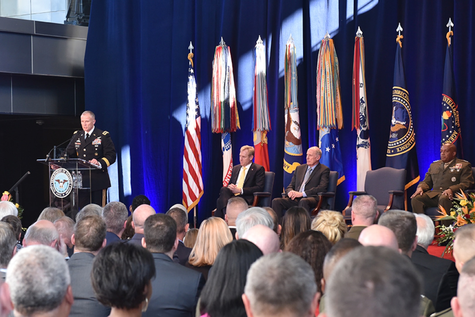 DIA Director Lt. Gen. Robert Ashley, Jr. addresses the crowd with Deputy Secretary of Defense Patrick Shanahan (back left), Director of National Intelligence Daniel Coats (back center) and former DIA Director Vincent Stewart (back right) looking on during the Change of Directorship Ceremony Oct. 3 at DIA Headquarters in Washington, D.C.