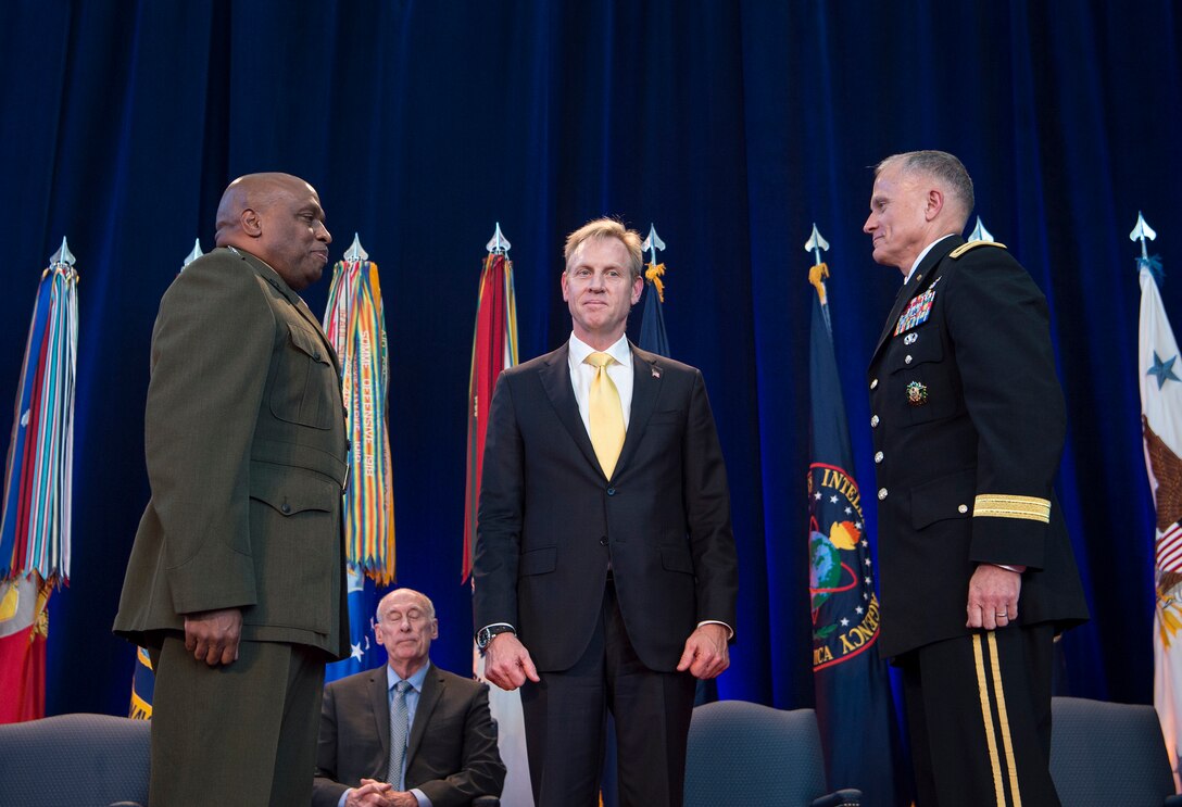 Deputy defense secretary stands between generals.