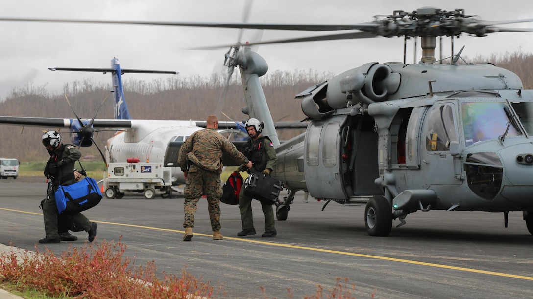 U.S Marine Maj. Robert Gill, the officer in charge of Joint Task Force - Leeward Island’s security element, helps U.S. sailors with Helicopter Sea Combat Squadron 22 unload luggage from a U.S. Navy SH-60 Seahawk helicopter at Douglas-Charles Airport in Melville Hall, Dominica, Sept. 25, 2017. Gill and his Marines provide security and stability at landing zones and at the U.S. Department of State’s evacuation control center at the airport. At the request of partner nations and both the Department of State and the U.S. Agency for International Development, JTF-LI has deployed aircraft and service members to areas in the eastern Caribbean Sea affected by hurricanes Irma and Maria. The task force is a U.S. military unit composed of Marines, Soldiers, Sailors and Airmen, and represents U.S. Southern Command’s primary response to both disasters.