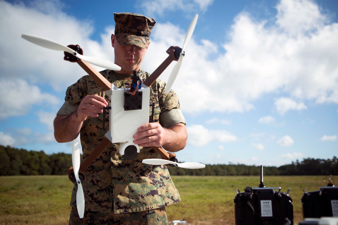 A Marine standing outside holds a drone.