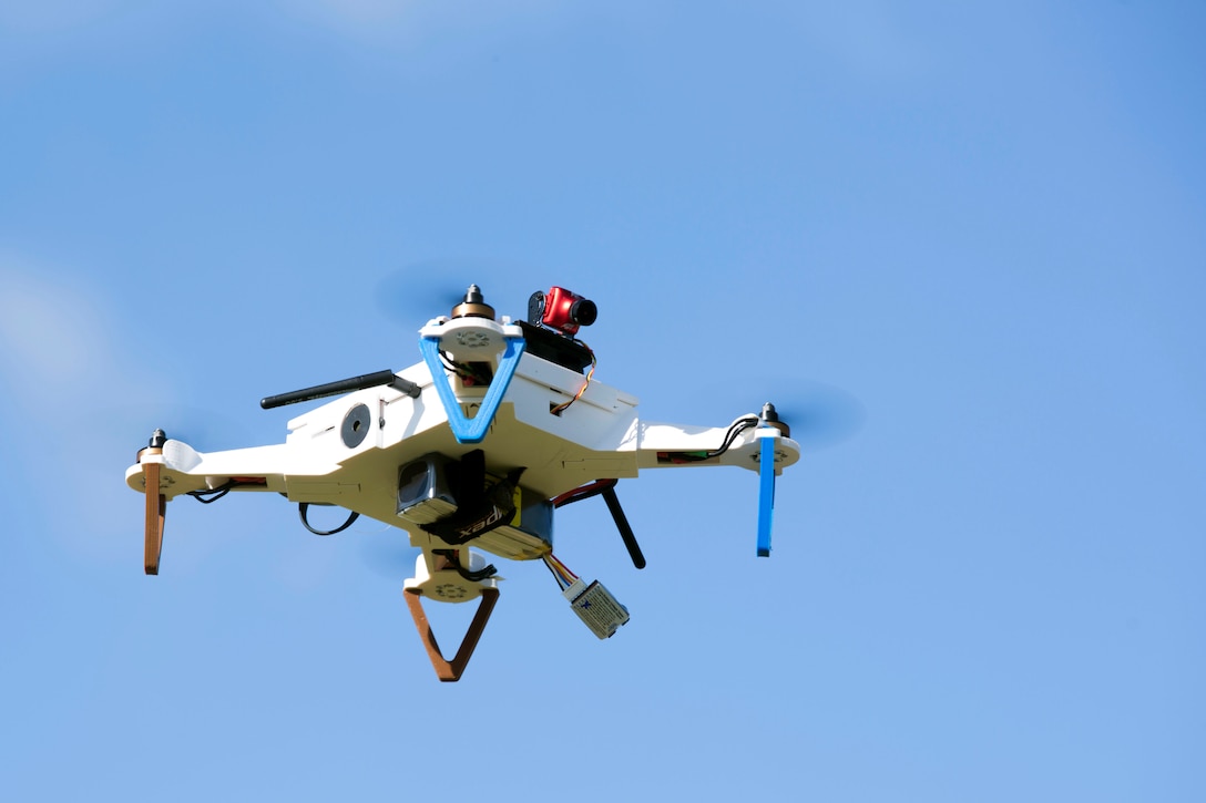 A drone flies against a blue sky.