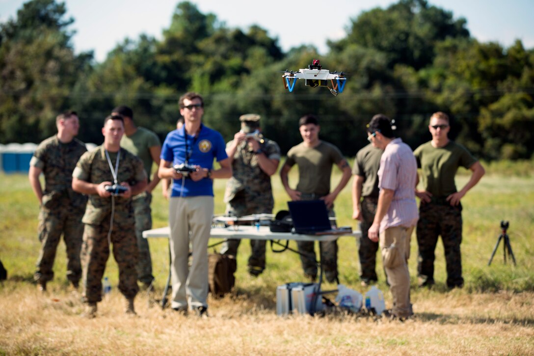 A group of people watch a drone fly.