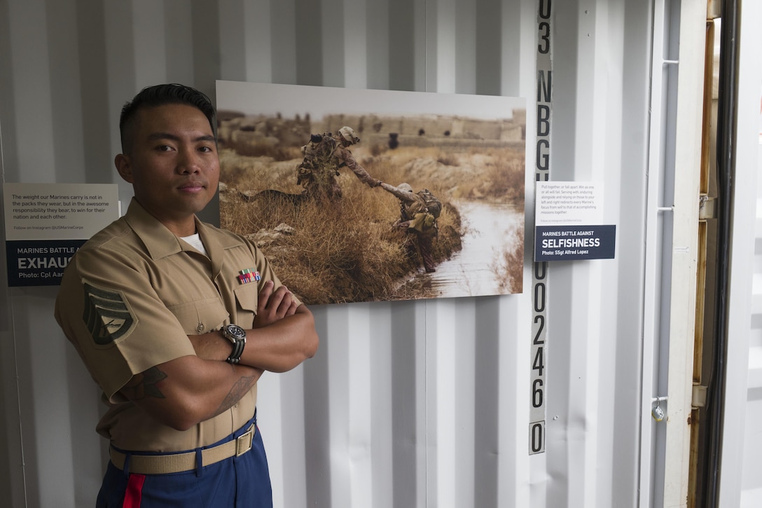 Staff Sgt. Alfred Lopez, a Marine photojournalist from Union, New Jersey, stands next to his photo of Marines crossing a canal in Afghanistan, which was featured at Photoville in Brooklyn, New York, September 21, 2017. Photoville is an annual a photography exhibition hosted under the Brooklyn Bridge in the Dumbo neighborhood. The Marine Corps participated in the exhibition for the first time by showing photography that embodied the Marines’ current brand idea of “Battles Won.”  (U.S. Marine Corps photo by Sgt. Bryan Nygaard)