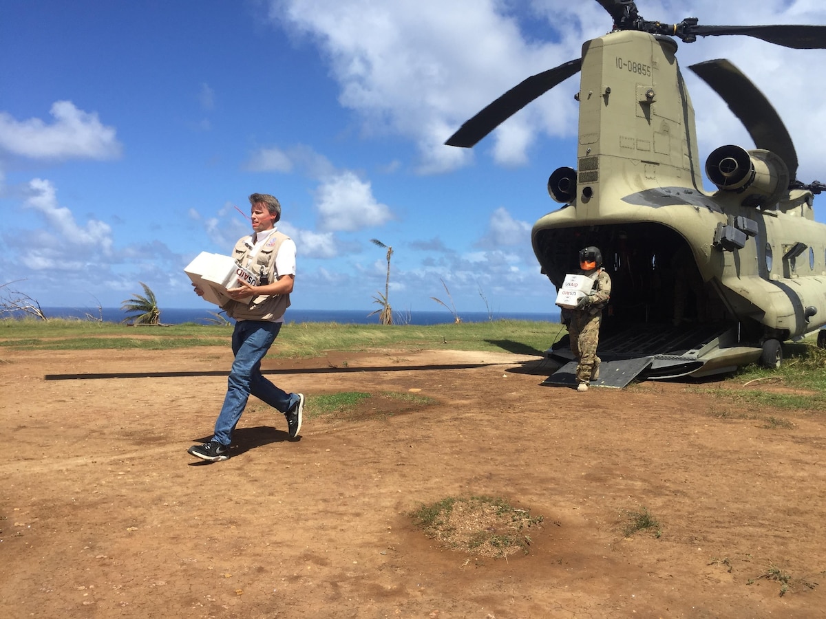 U.S. officials and service members unload aid from helicopter for distribution to the people of Dominica