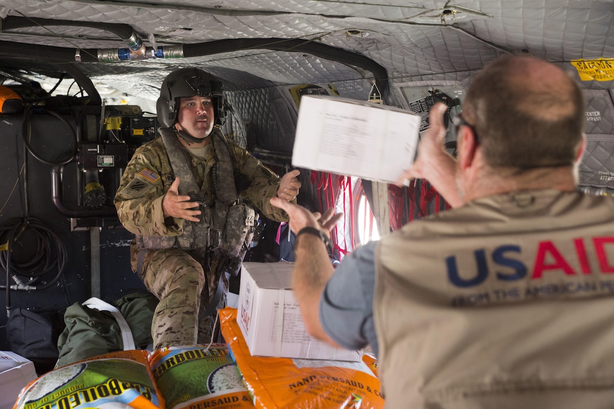 A Soldier  helps load kitchen sets and bags of rice on a U.S. Army CH-47 Chinook helicopter at the port of Roseau, Dominica.