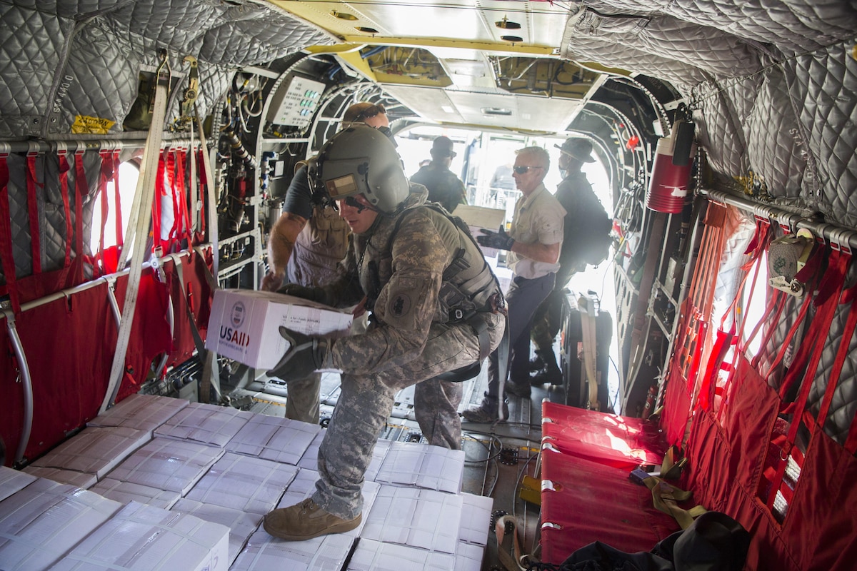 A Soldier helps load kitchen sets on a U.S. Army CH-47 Chinook helicopter at the port of Roseau, Dominica.