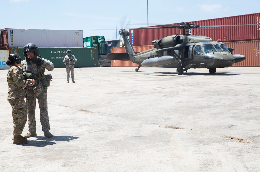 A Soldier coordinates air support for relief operations with the crew of a helicopter in Roseau, Dominica.