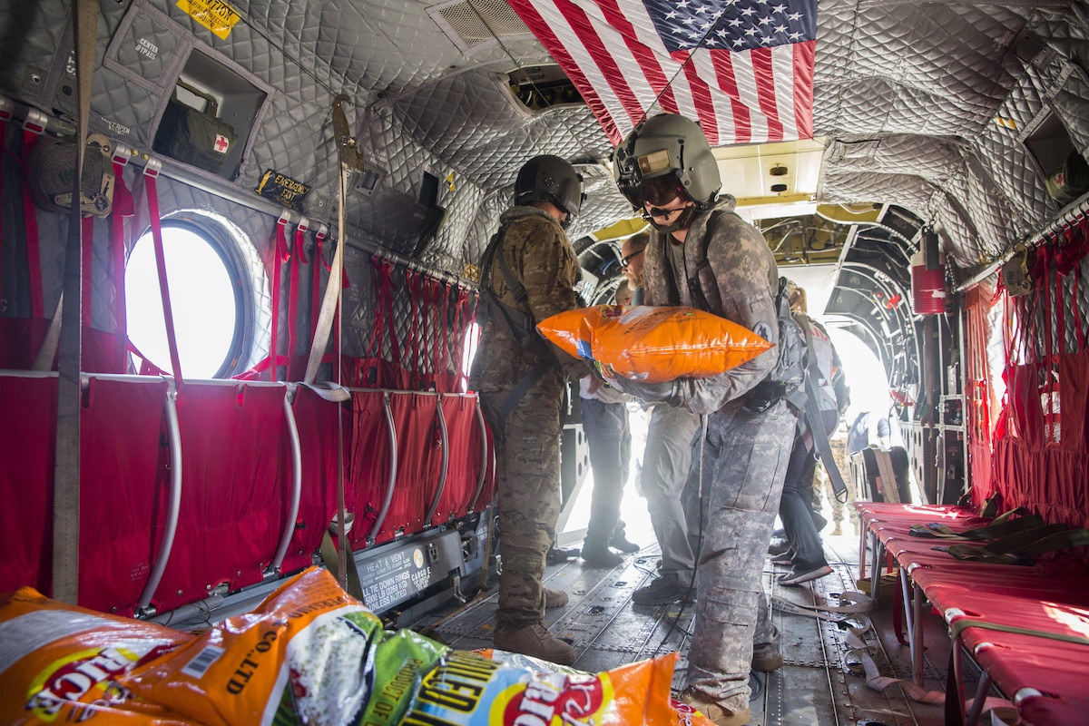 A Soldier helps load rice on a U.S. Army CH-47 Chinook helicopter at the port of Roseau, Dominica.