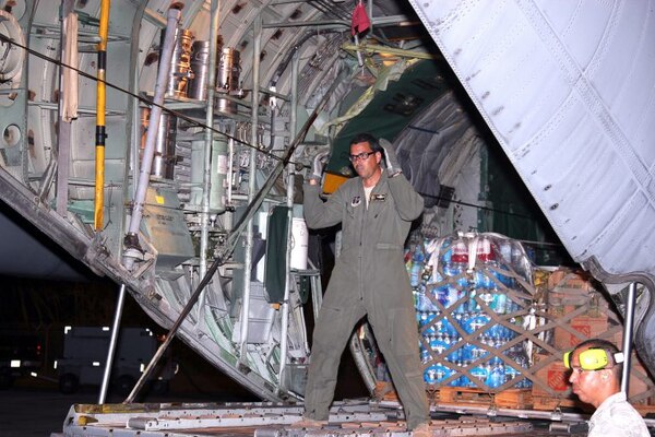 A man stands in the rear opening of a C-130 Hercules aircraft.