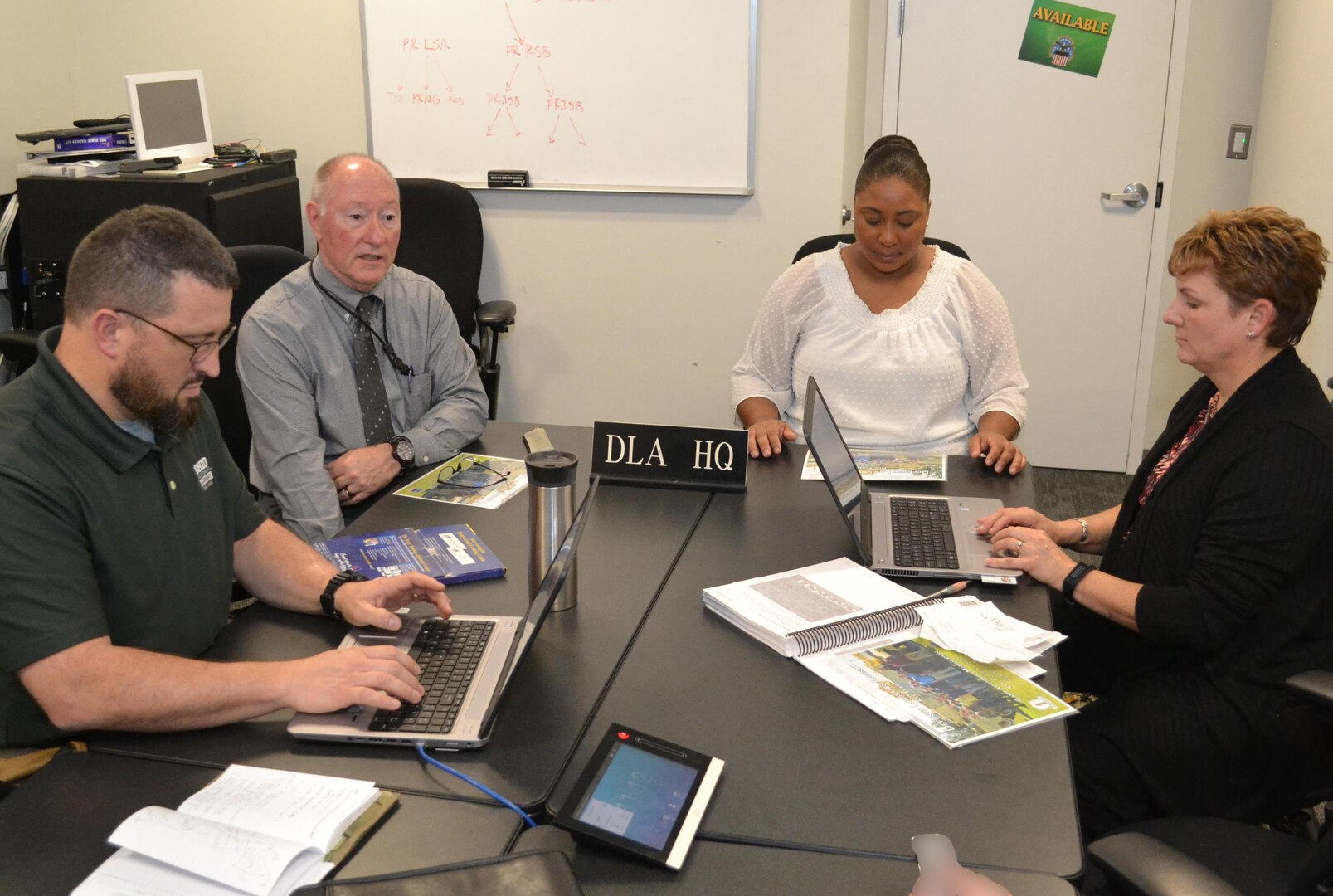 People sit around a table crowded with papers and laptops