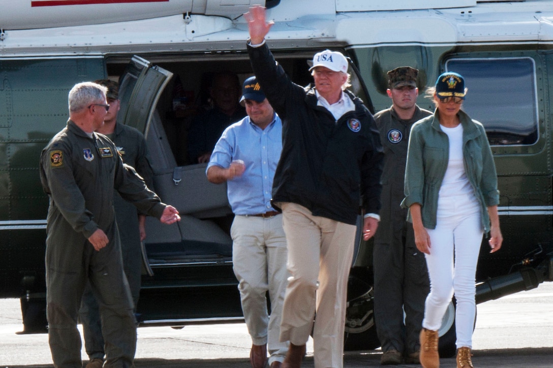 The president waves near a helicopter with the first lady nearby.