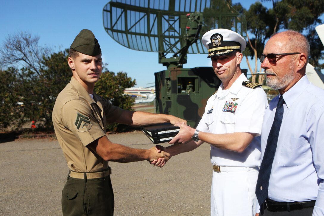 Capt. Joseph Hornbuckle III, right, the Naval Air Traffic Management Systems Program officer, and Cpl. Mitchell Huffman, an air traffic control radar technician, exchange the official maintenance logbooks from the TPN-22 and a TPS-73 radar systems at Marine Corps Air Station Miramar, Calif., Sept. 28. Following an earlier retirement ceremony at MCAS Yuma, the TPN-22 and the TPS-73 radar systems were officially retired and put on display for museum visitors to enjoy. Both radar systems were used for tracking and guiding aircraft in forward deployed scenarios when air traffic control towers were not available. (Marine Corps photo by Sgt. David Bickel/Released)