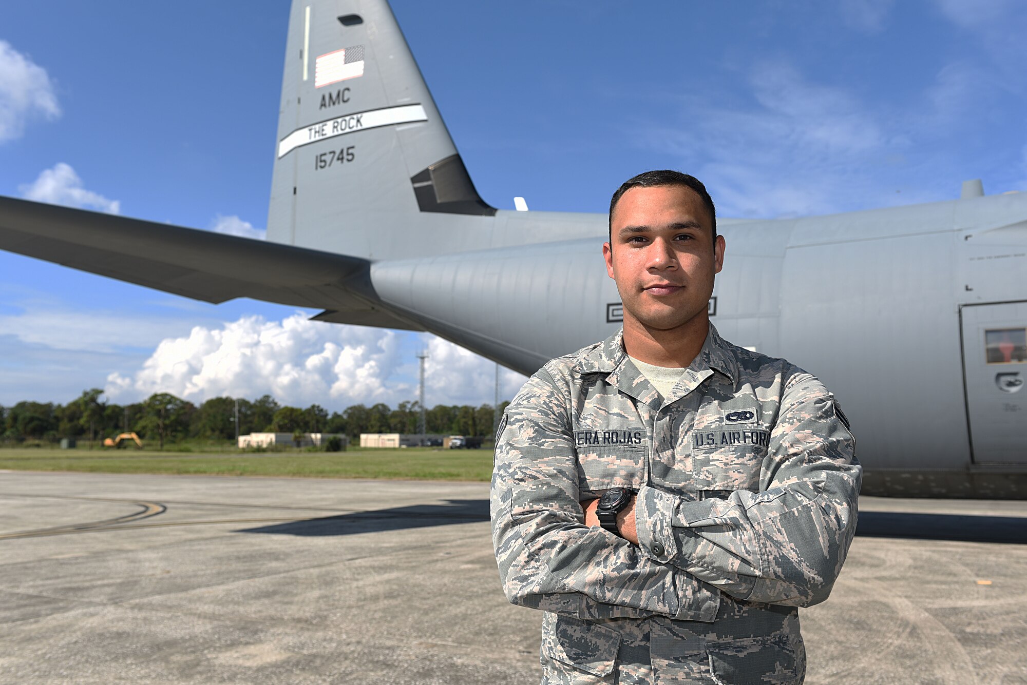 Male Airman stands in front of aircraft tail