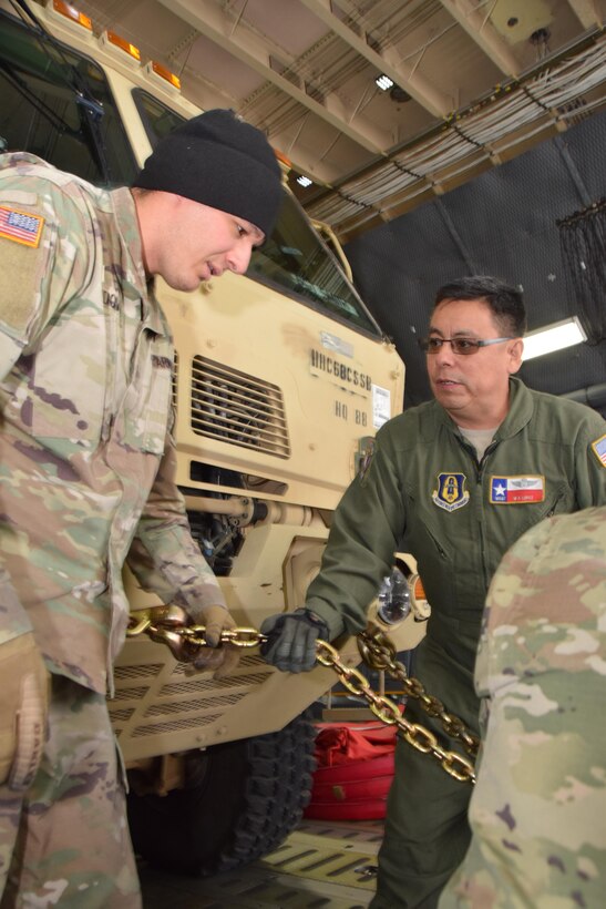 Master Sgt. Michael Lopez (right), a 68th Airlift Squadron loadmaster, instructs U.S. Army Specialist Nicholas Sandoval (left), an automated logistics specialist with the 247th Composite Supply Company, 68th Sustainment Support Battalion, 4th Sustainment Brigade, 4th Infantry Division, on how to secure a vehicle on an Air Force Reserve Command C-5M Super Galaxy prior to departing from Colorado Springs, Colorado, Oct. 1, 2017.  (U.S.  Air Force photo by Tech. Sgt. Carlos J. Treviño)
