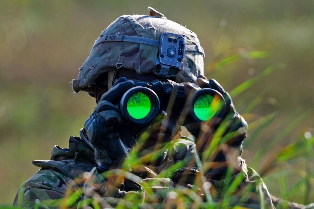 A soldier uses binoculars to scan the area while participating in the Polish national defensive exercise, Dragon 17.