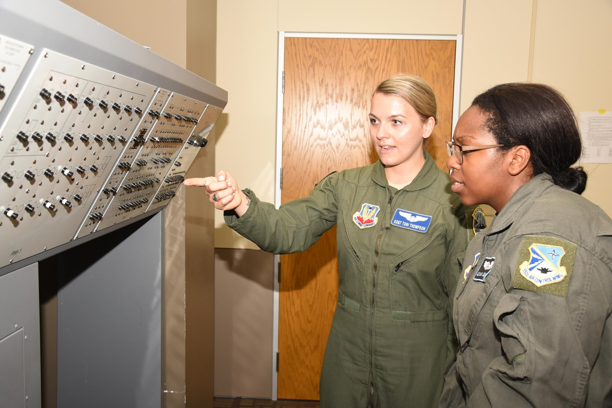 Staff Sgt. Victoria Thompson, left, an instructor with the 966th Airborne Air Control Squadron, explains the various functions of the P66-1 circuit breaker panel to Airman 1st Class Hannah Jean-Marie from the 552nd Training Squadron.