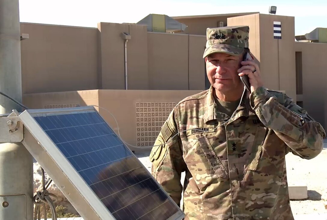 Major General Edward Dorman, director for logistics, U.S. Central Command, charges a hand-held portable device from a USB port powered by a solar powered light cart at Camp Arifjan, Kuwait. The carts are part of an operational energy initiative to reduce USCENTCOM's carbon footprint and reliance on fossil fuels. (379th Air Expeditionary Wing Public Affairs courtesy image)