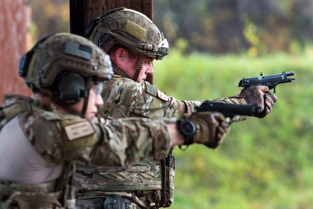 Two airmen aim pistols at an unseen target.