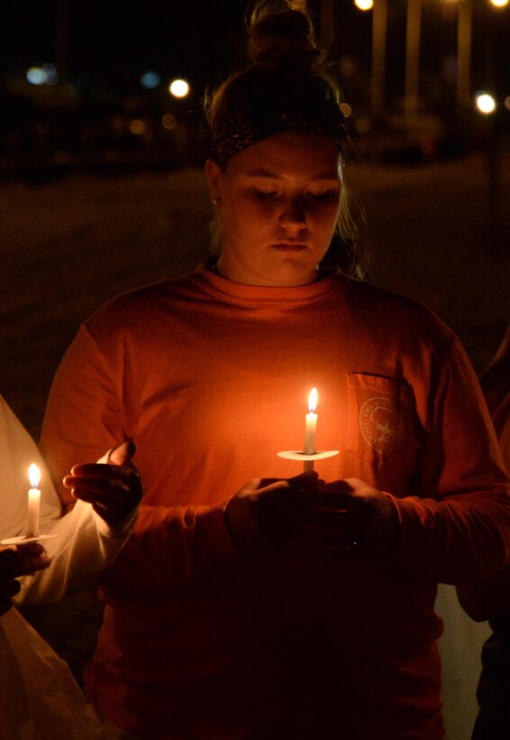 A person looks at a candle she is holding.