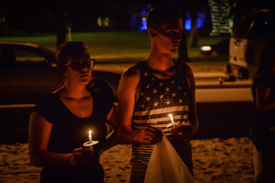 Two airmen stand holding candles.