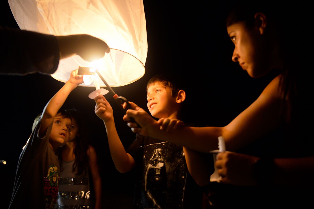 A group of people light a candle inside a lantern.