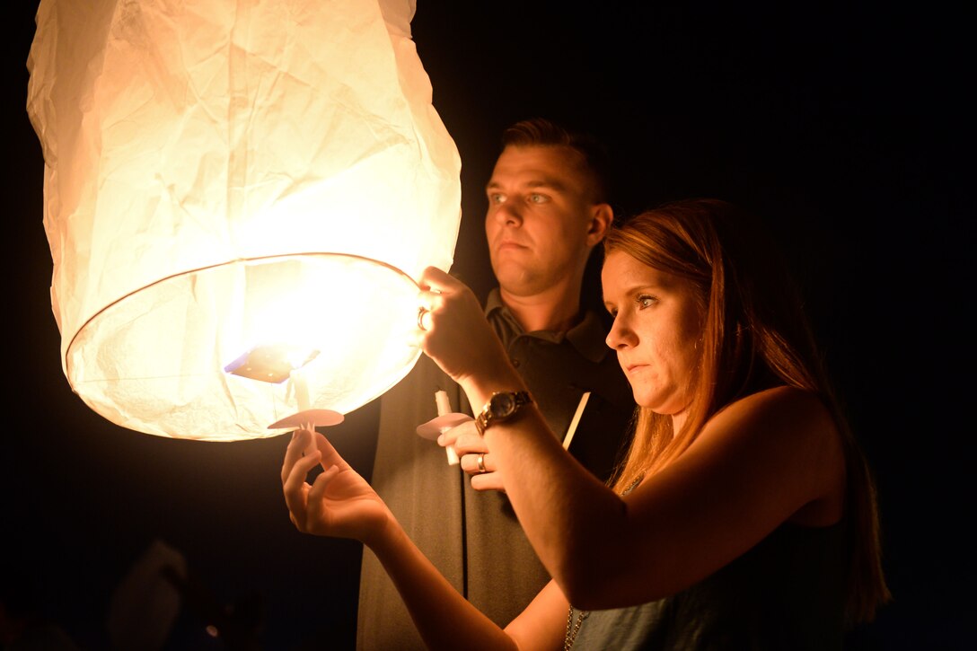 Two people light a candle inside a sky lantern.