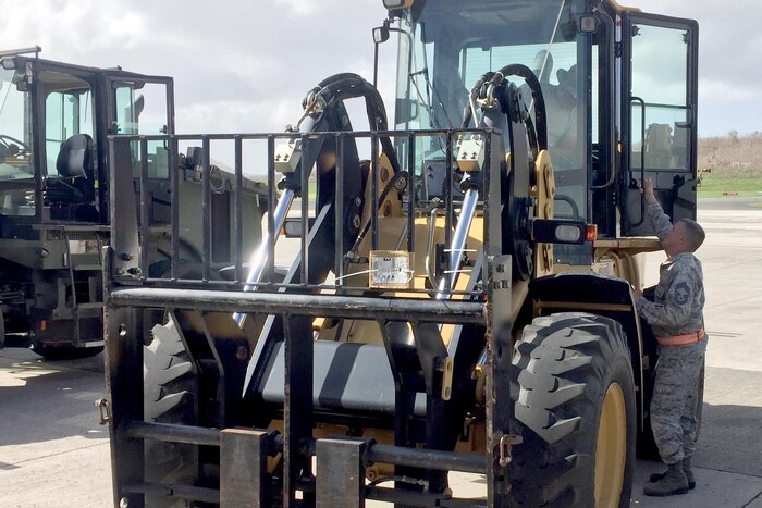 An airman climbs into a forklift