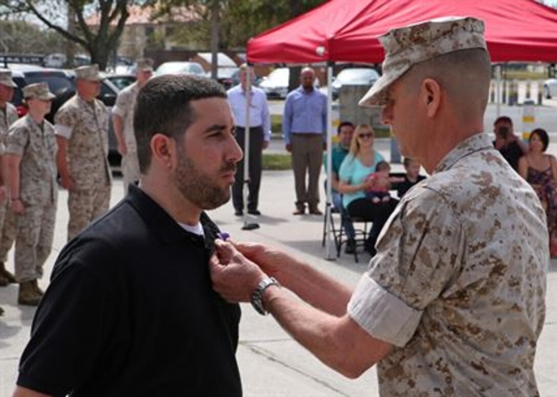 Corporal Brian P. Johnson is presented the Purple Heart medal by Lieutenant. Gen. William D. Beydler, Mar. 17, 2016, at a ceremony at MacDill Air Force Base, Fla. Johnson received the Purple Heart for injuries he sustained on 26 July 2006, during combat operations with Combined Regimental Combat Team 5, in Fallujah, Iraq. Johnson completed his active service in November of 2006. Beydler is the commander of Marine Corps Forces Central Command.