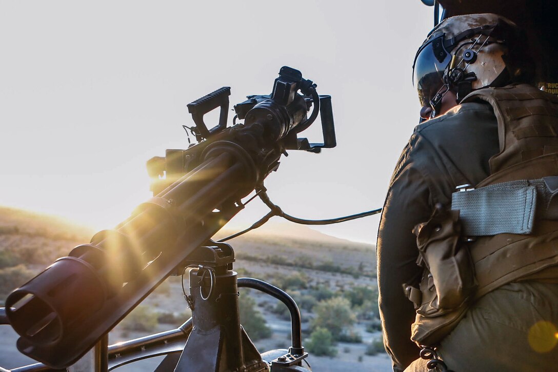 A Marine stands near a firearm.