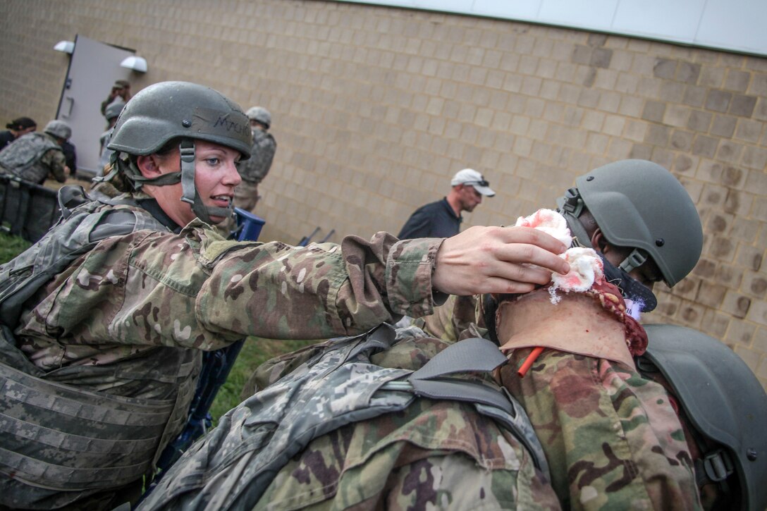 An airman holds a bandage on a simulated patient.