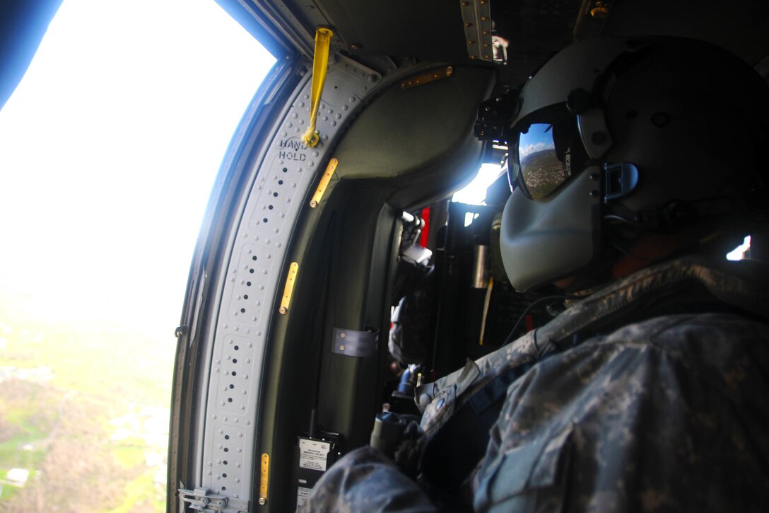 A guardsman looks the door of a helicopter.