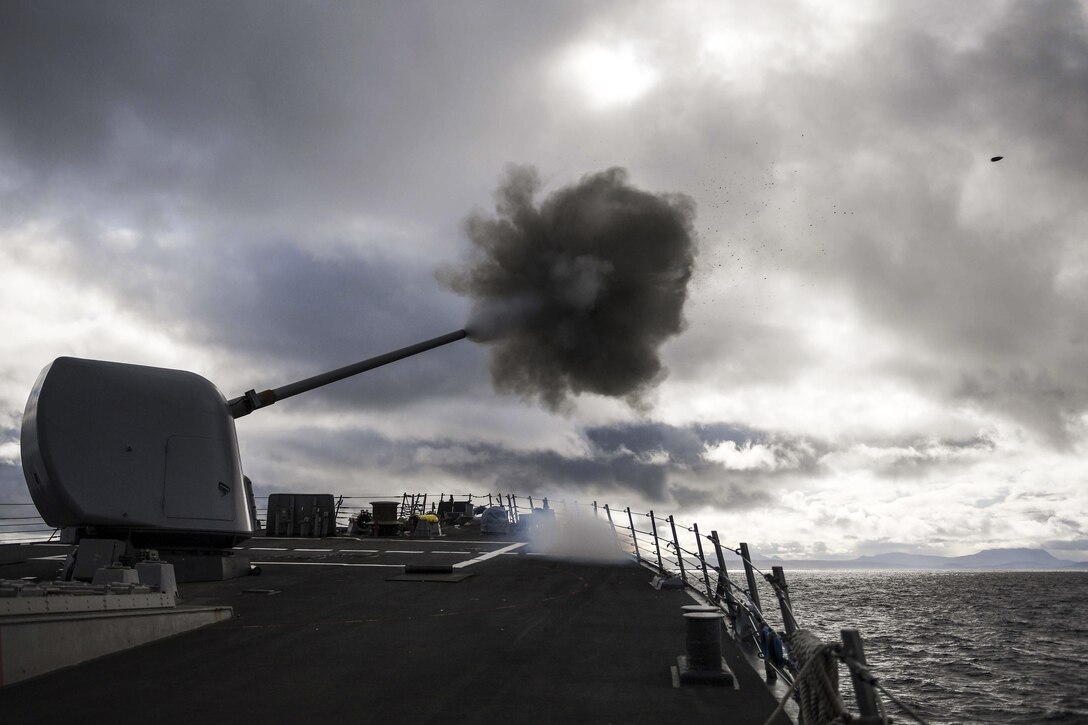 A ship fires a weapon at sea into cloudy skies