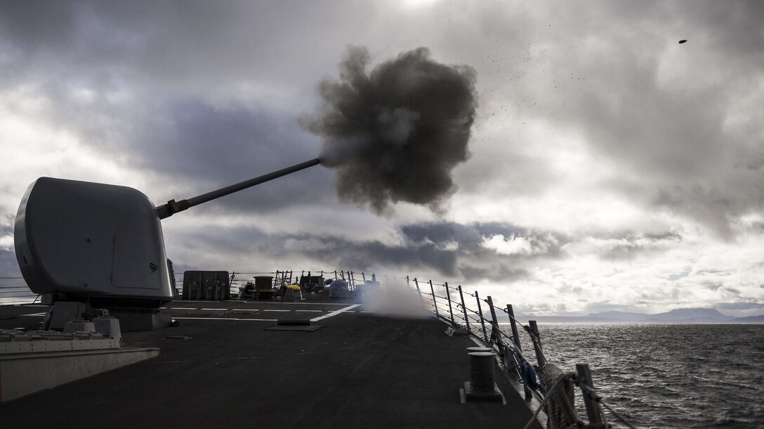 A ship fires a weapon at sea into cloudy skies