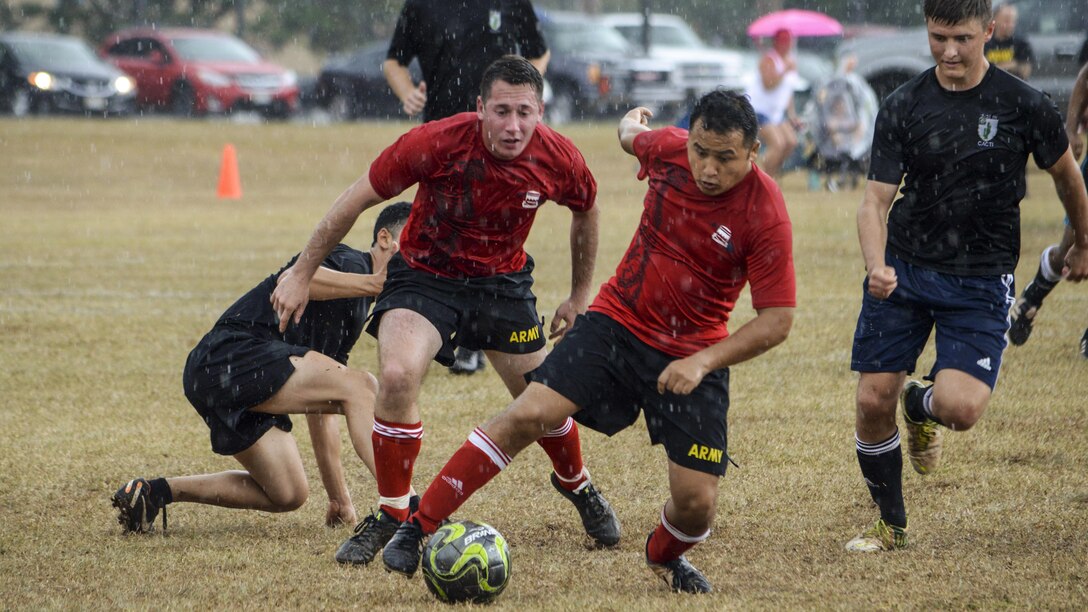 Soldiers play soccer in the rain.