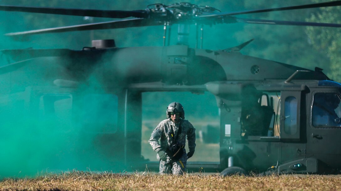 A soldier runs through smoke toward the camera.