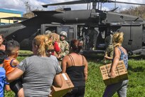 Soldiers deliver boxes of aid to residents following a hurricane.