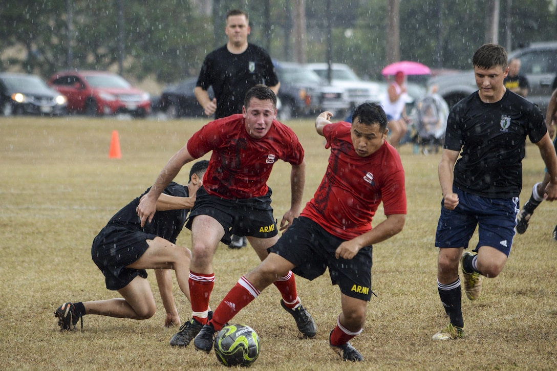 Soldiers play soccer in the rain.