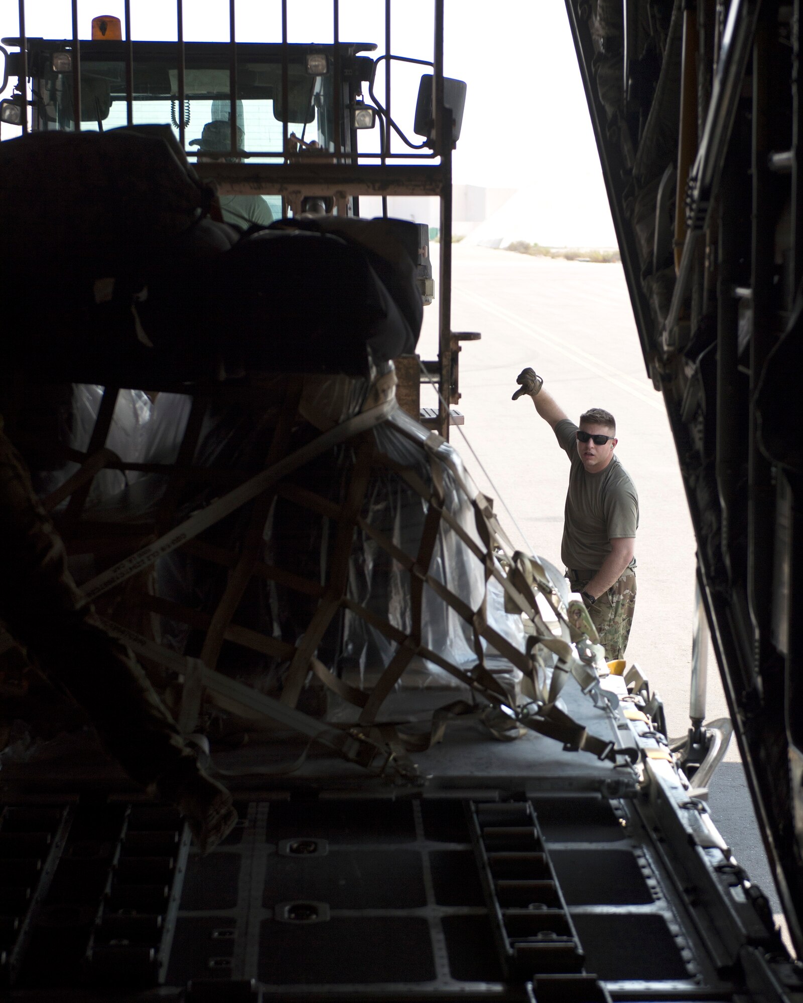 U.S. Air Force Tech. Sgt. Ronald Toia, loadmaster with the 746th Expeditionary Airlift Squadron, gives directions to an air transport specialist with the 380th Expeditionary Logistics Readiness Squadron, Air Terminal Operations Center, at Al Dhafra Air Base, United Arab Emirates, Oct. 3, 2017.
