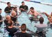 Col. Richard Reed, 377th Force Support Squadron commander, coins all instructors from the 58th Operations Support Squadron in the pool after training.  Airmen from the 377th Force Support Squadron and 150th Special Operations Wing completed an overturned-aircraft simulation, compressed-air breathing exercises and various parachute escape exercises.