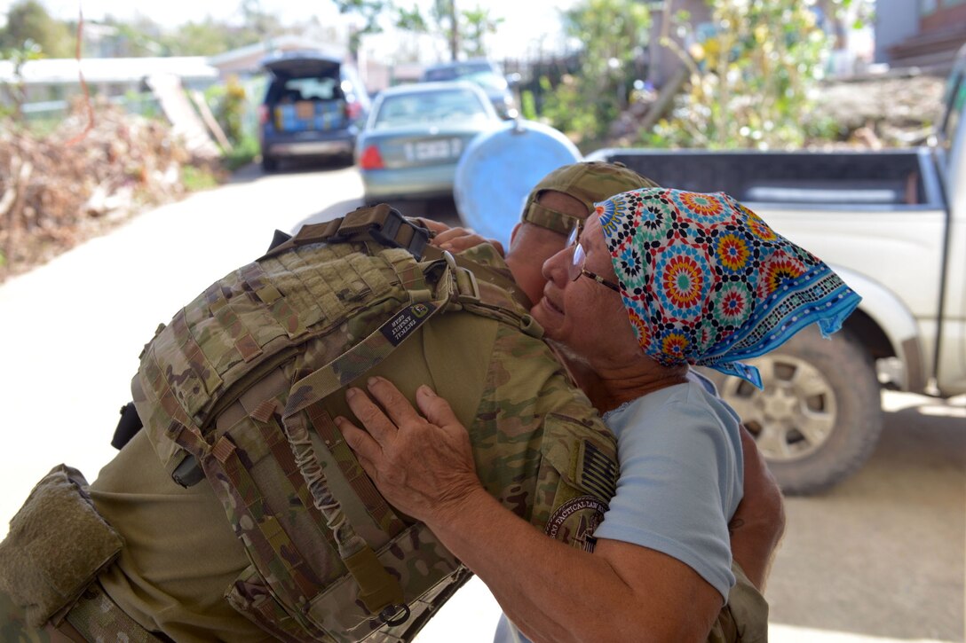 A local resident embraces a Coast Guard service member as Hurricane Maria relief supplies are distributed to victims in Bayamon, Puerto Rico.