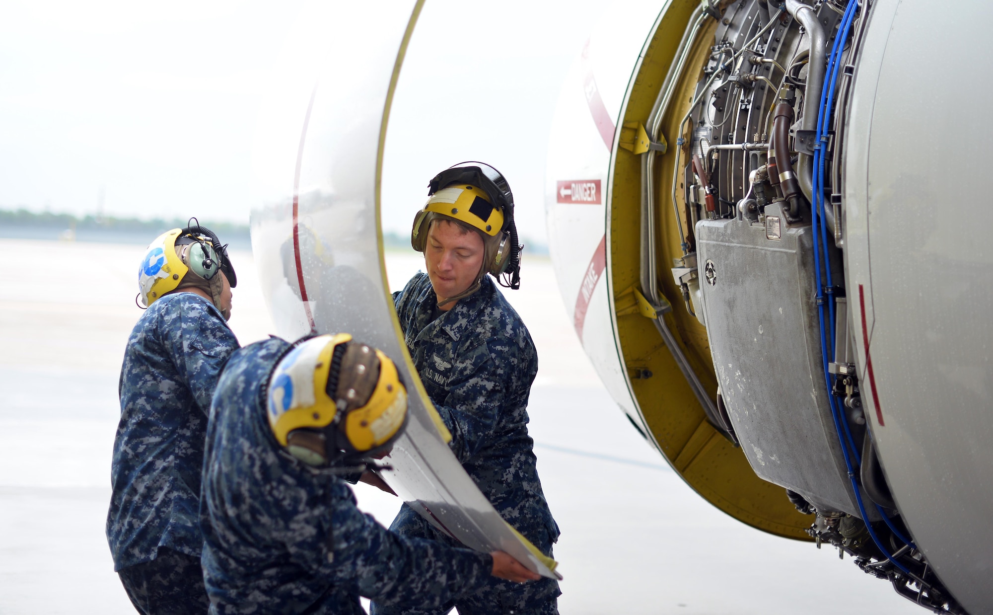 U.S. Navy Strategic Communications Wing ONE Detachment Sailors Airman Alfredo Valdez, Airman Benaiah Hague, and Petty Officer Petty Officer Third Class Jurgen Baezabernal open the engine cowling to service oil during a turn-around inspection on an E-6 Mercury here Oct. 3.