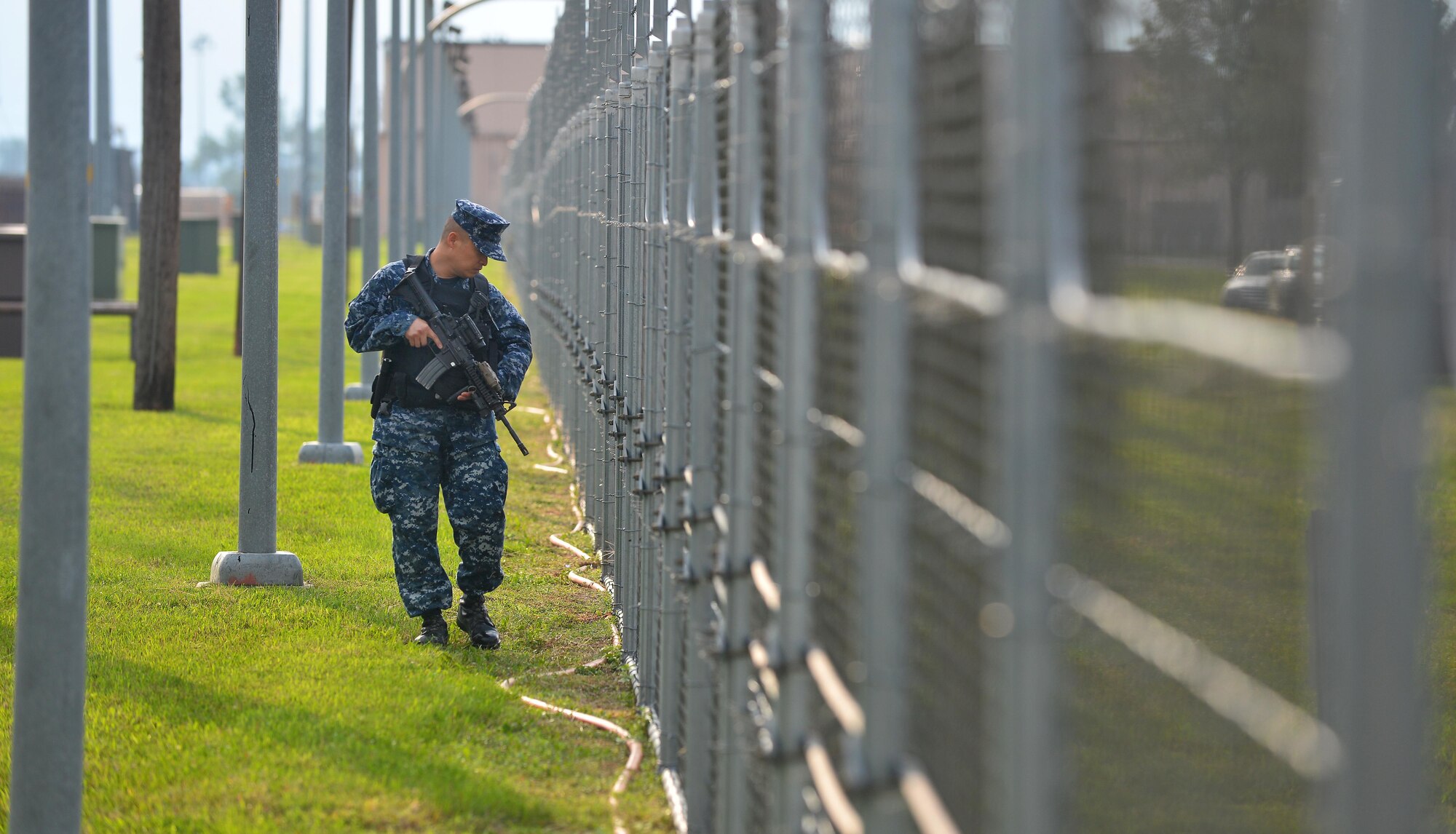 U.S. Navy Petty Officer Second Class Giovanni Alegado, 55th Security Forces Squadron master at arms, walks the flightline fence here during a routine security check Oct. 3.