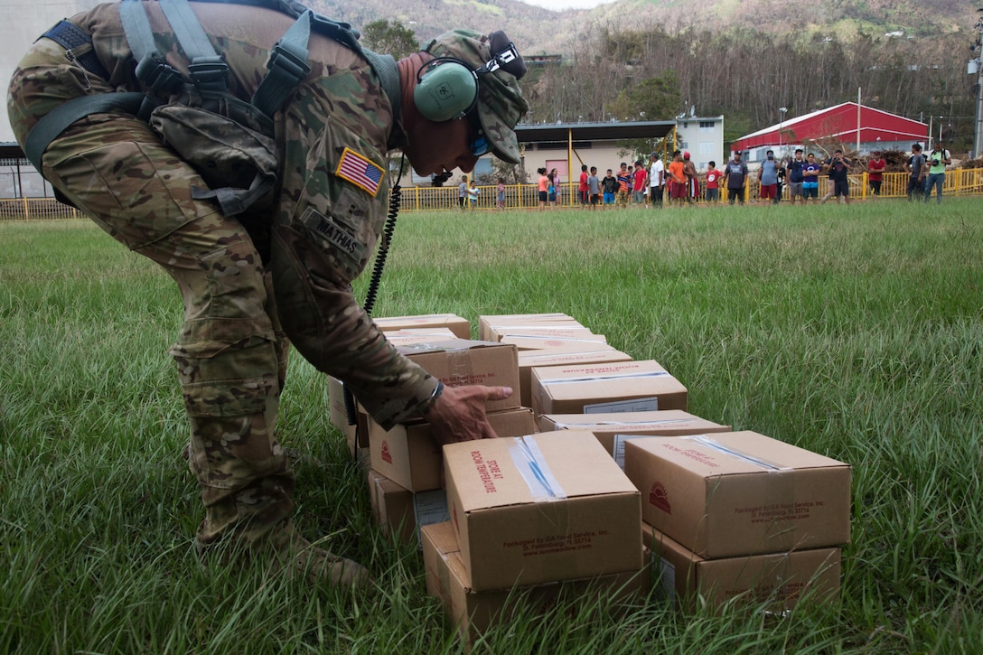Army Chief Warrant Officer 2 Barry K. Mathias, assigned to the 101st Combat Aviation Brigade,  unloads boxes of food from a UH-60 Black Hawk in Jayuga, Puerto Rico.