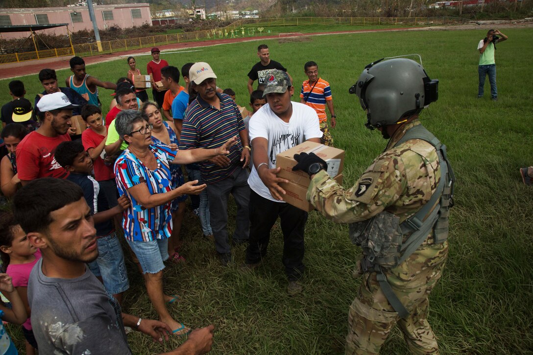 A soldier hands boxes of food to locals in Jayuga, Puerto Rico.