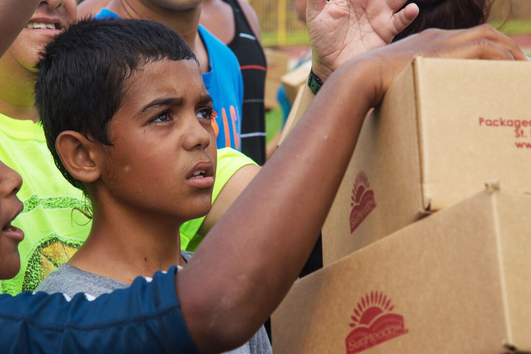 Soldiers hand boxes of food to locals in Jayuga, Puerto Rico.